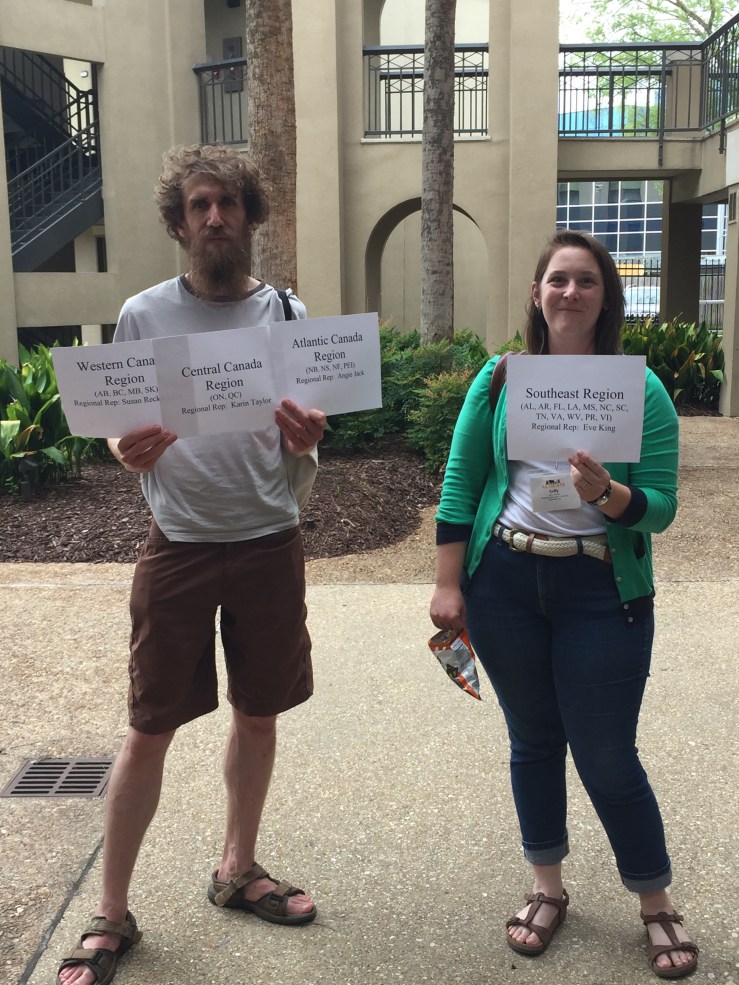 Julian and Kelly hold up signs for the regional meetings. High praise for Julian's multitasking.