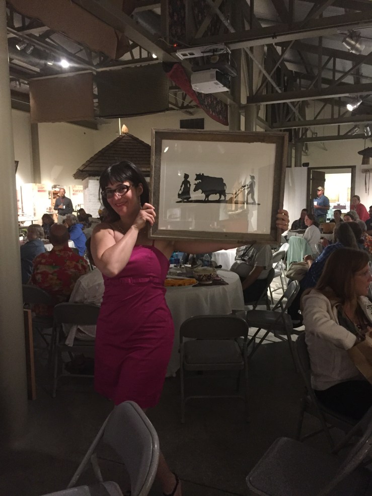 Marie-Sophie Desaulniers does her best Vanna White holding up a beautiful framed original of the new logo that was hand it by silhouette artist Lauren Muney